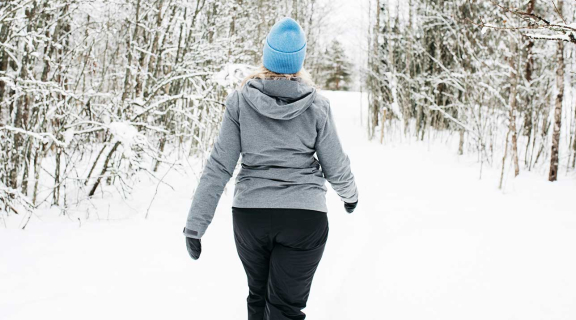 Kvinna på promenad i en snöklädd skog.