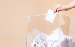 Käsi tiputtaa äänestyslappua tai tyhjää lappua laatikkoon.