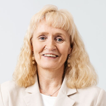 Vaaleahiuksinen nainen tummassa mekossa.