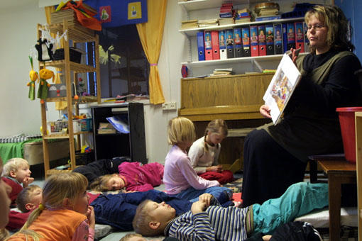 Barn ligger på golvet och lyssnar på saga
