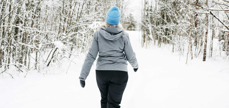 Kvinna på promenad i en snöklädd skog.